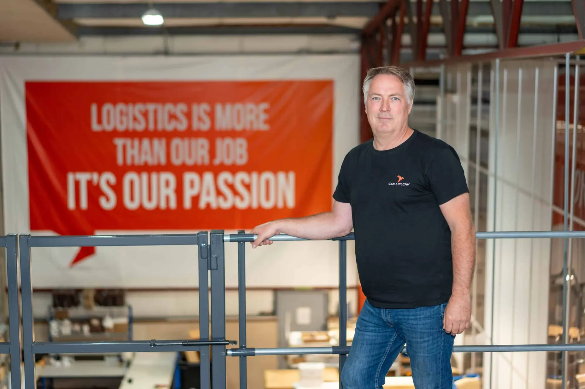 Medarbeider foran banneret «Logistics is more than our job – it's our passion» i lagerhallen