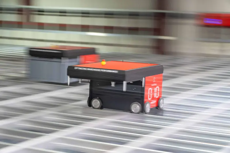 AutoStore-robot med rødt lys i fart over rutenettet