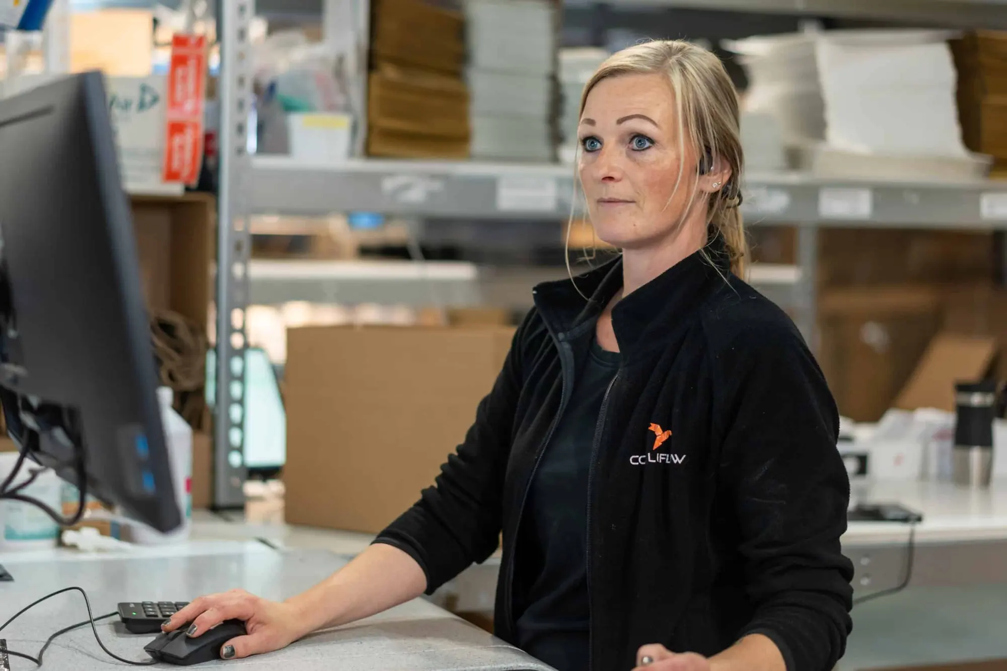 Medarbeider ved dataskjermen på pakkestasjonen