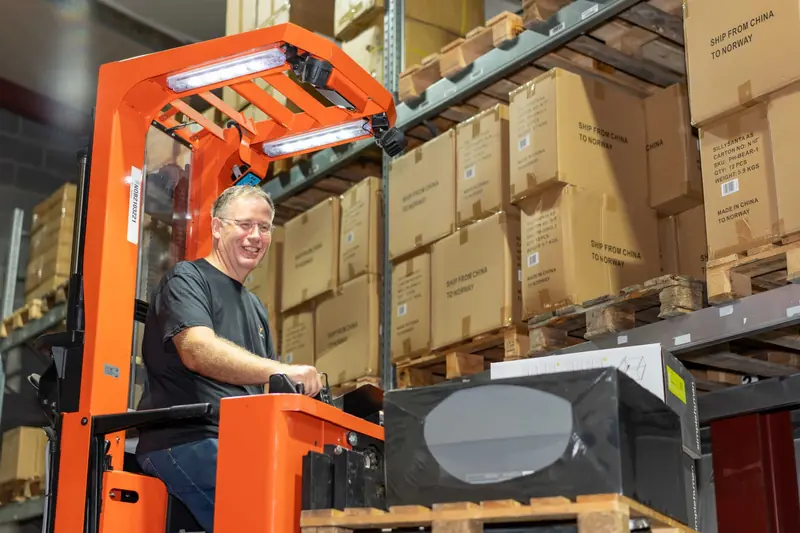 Lagermedarbeider på truck foran fylte pallereoler